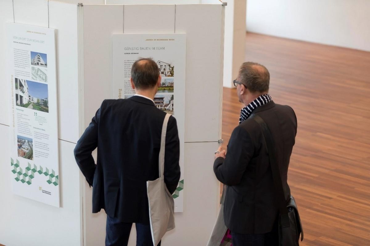 Menschen bei der Fachkonferenz Wohnen vor Ausstellungswänden
