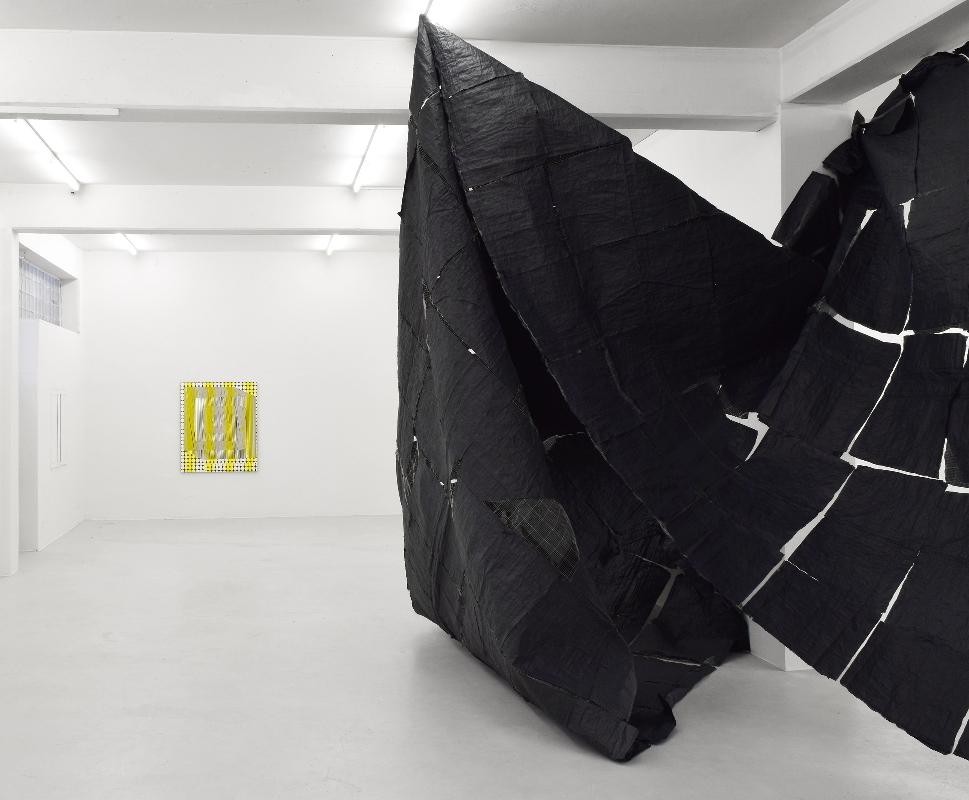 gelbe Struktur auf Holz von Christof John, schwarzes raumgroßes Gebilde aus Seidenpapier und Olivennetz von Olga Jakob
