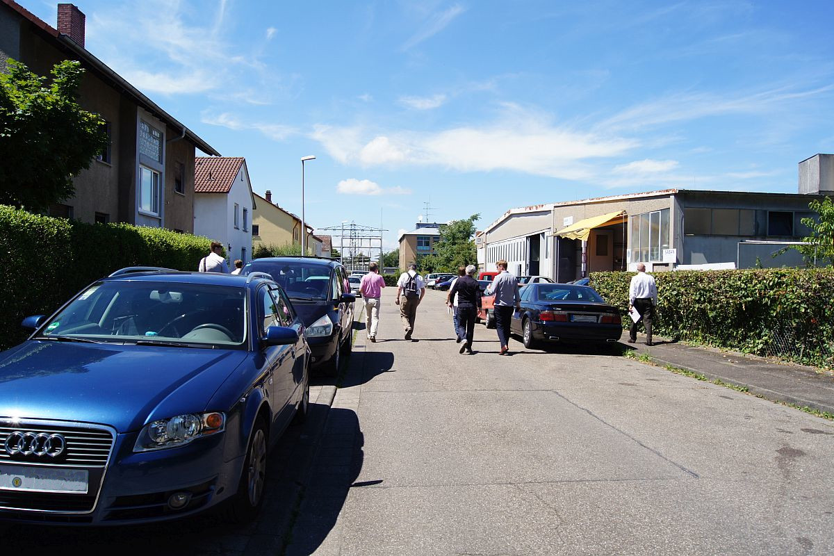 Schmale Straße mit parkenden Autos und Spaziergängern