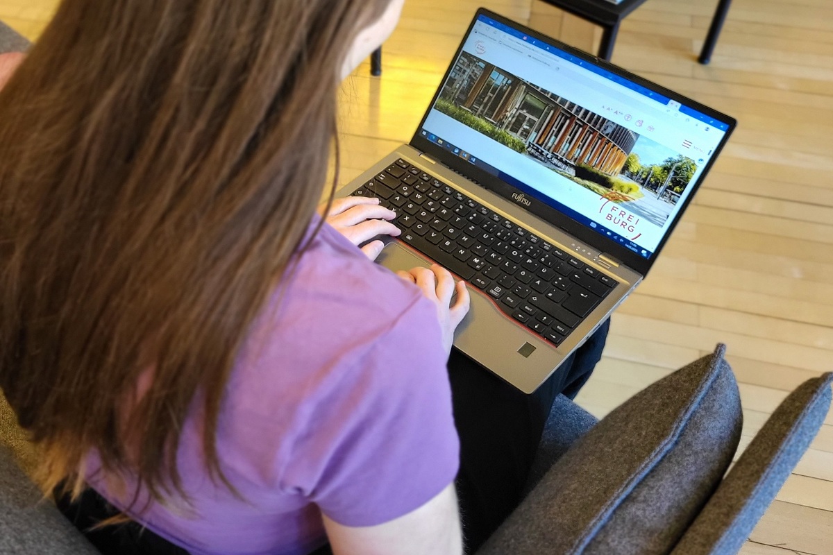 Ein Über-die-Schulter Bild von einer Frau, die am Laptop die Webseite der Stadt Freiburg geöffnet hat.