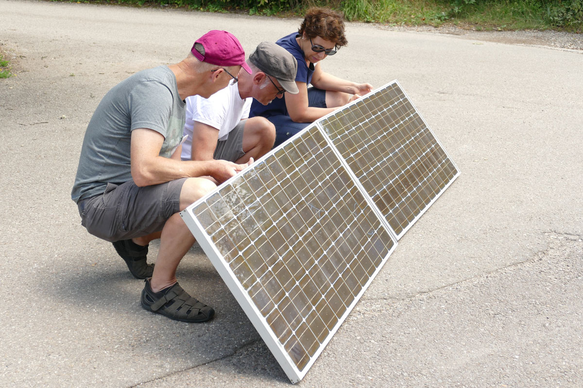 Drei Personen halten zwei Solarmodule