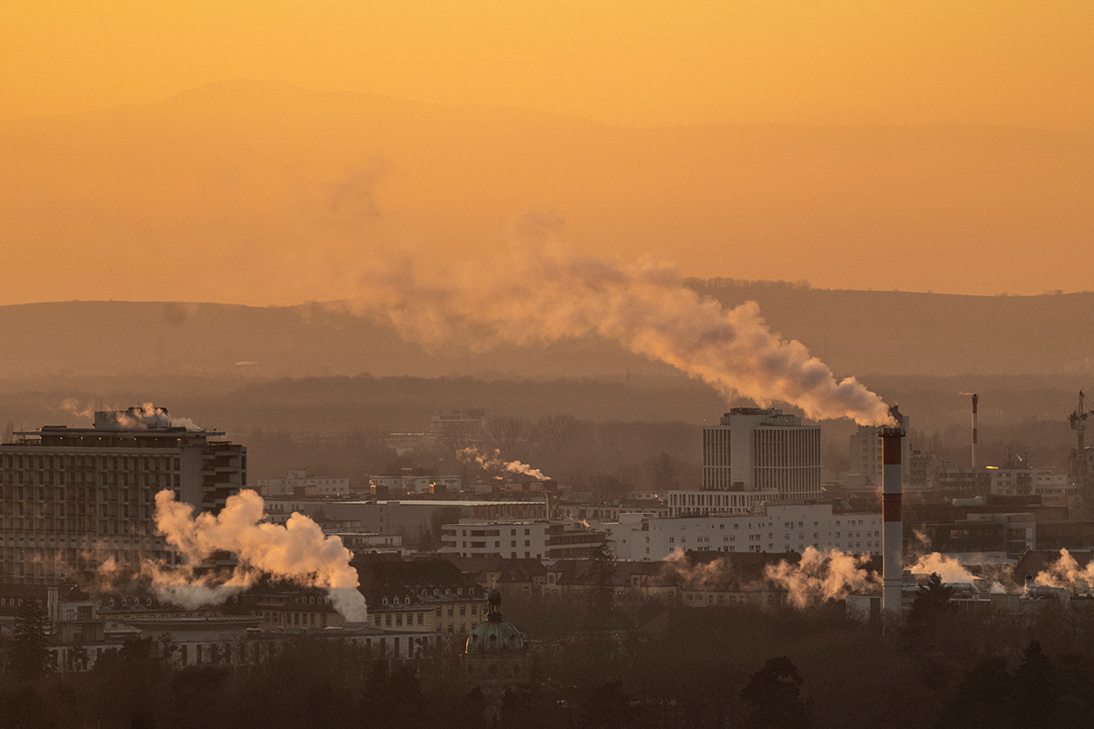 Rauchende Kamine über der Stadt im Sonnenuntergang
