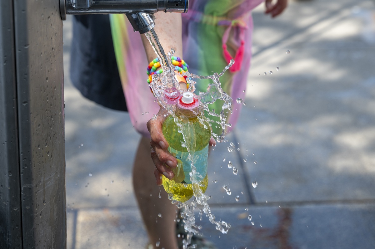 Eine Person hält eine Wasserflasche unter einen Trinkwasserbrunnen, um sie aufzufüllen.