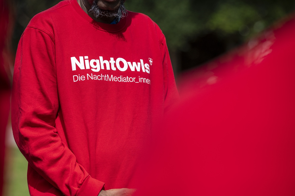 Eine Person trägt einen roten Pullover mit der Aufschrift: NightOwls - die Nachtmediator_innen