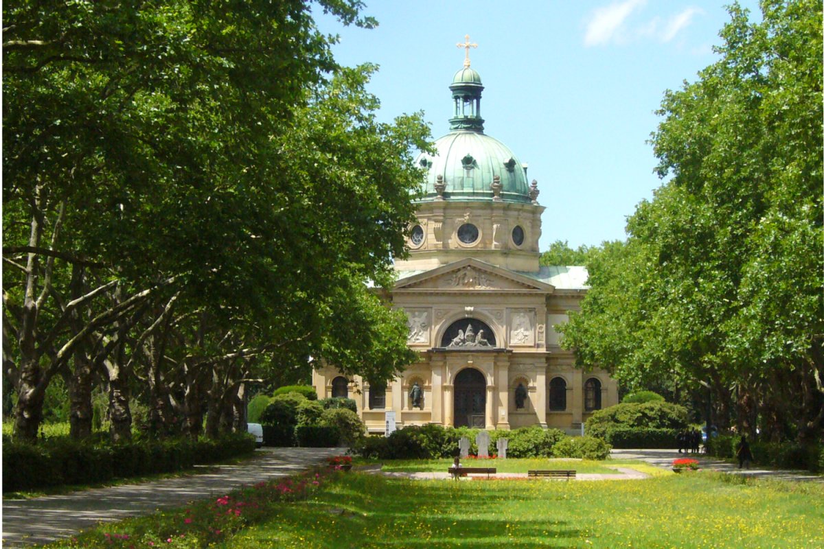 Baumallee, Wiese und Weg auf einem Friedhof mit Kuppelbau als Einegnungshalle