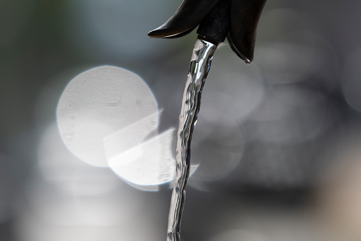 Ende eines Wasserhahns, aus dem fließendes Wasser kommt.