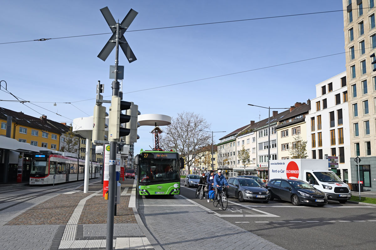 Bahn, Bus, Fahrrad und Auto an einer Ampel