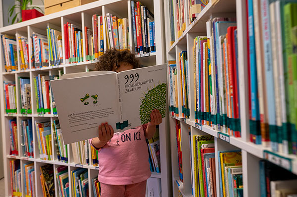 Kitakind hiter Buch vor Buchregal