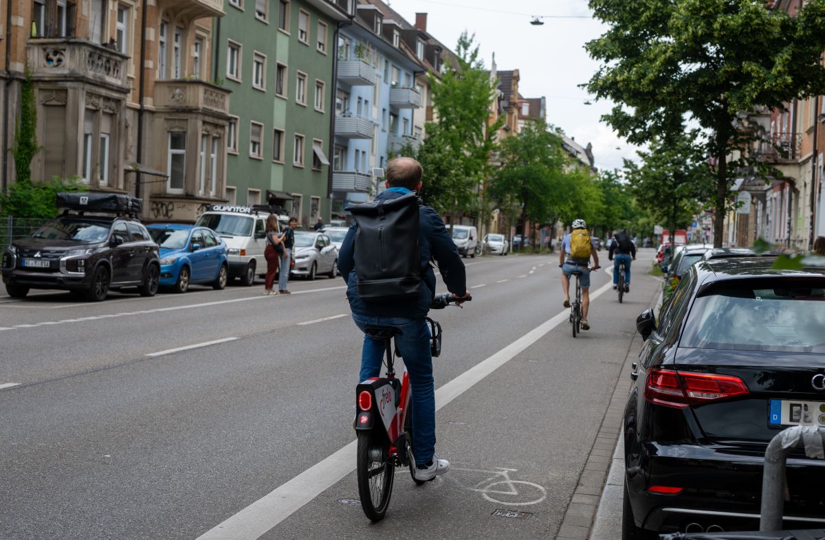 Radfahrer*innen fahren auf dem Radstreifen auf der Eschholzstraße an parkenden Autos vorbei.