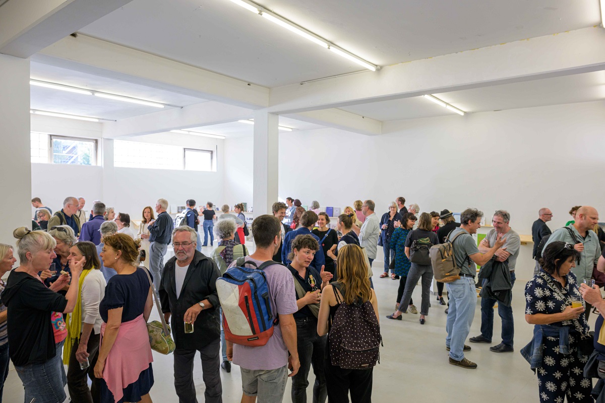 Eröffnung der Ausstellung "Abschied vom L6". Viele Menschen im Gespräch oder bei der Betrachtung von Katalogen zu sehen.