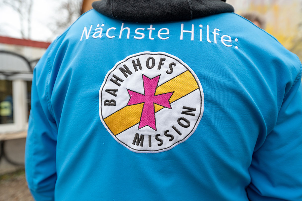 Blaue Jacke mit Aufschrift "Nächste Hilfe: Bahnhofsmission"