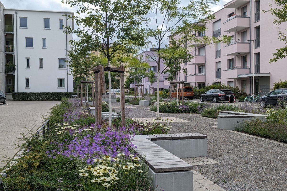 Blühende grüne Bereiche mit Sitzbänken und Spielbereich im Wohngebiet