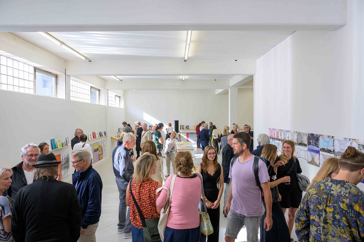 Eröffnung der Ausstellung "Abschied vom L6". Viele Menschen im Gespräch oder bei der Betrachtung von Katalogen zu sehen.