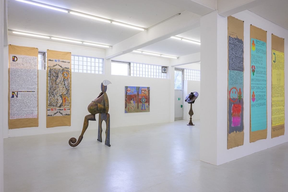 Ausstellungsansicht mit anziehbaren Skulpturen, Eitempera-Malerei und bemalten Packpapierbahnen