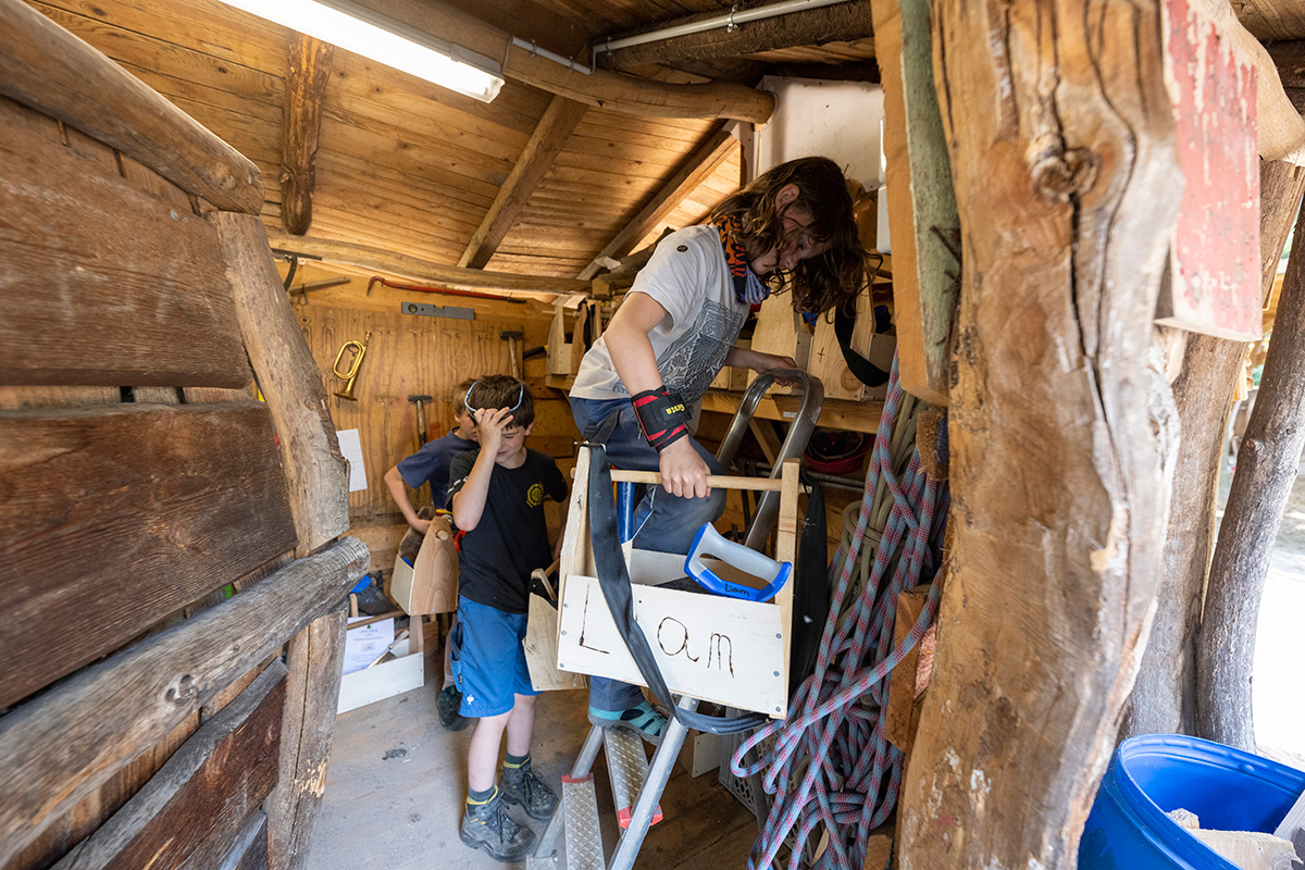 Drei Kinder mit Werkzeugkisten im Holzschuppen