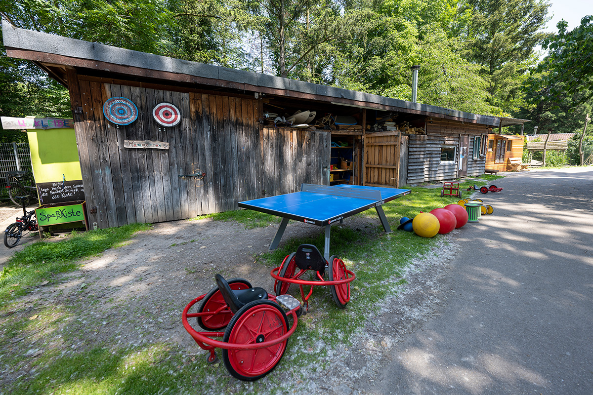 Holzhütte mit verschiedenen Spielgeräten davor