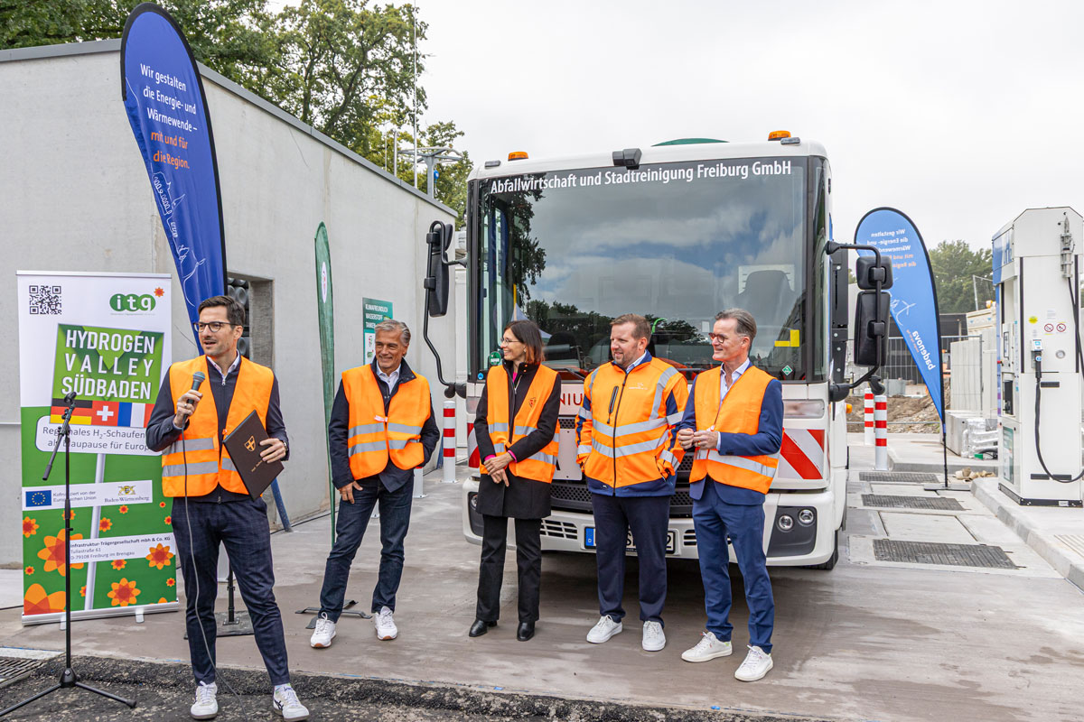 Mehrere Menschen stehen vor einem Wasserstoff-Fahrzeug