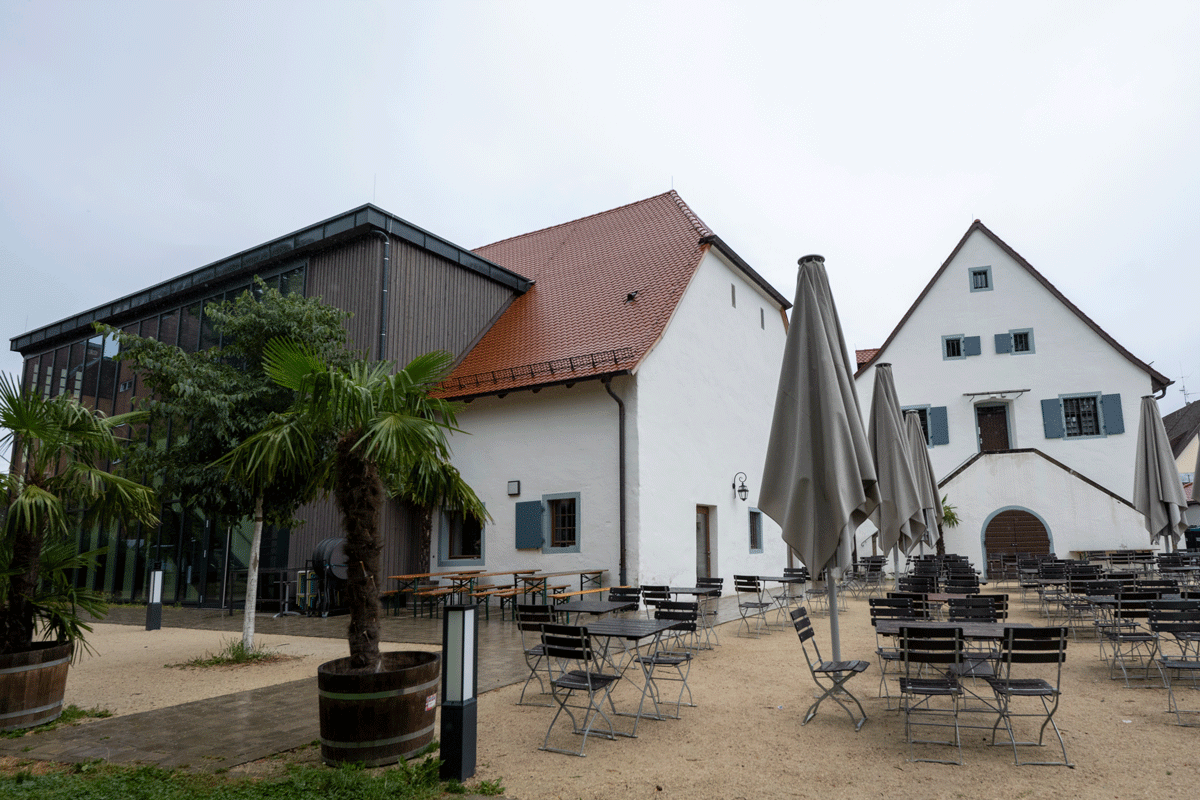 Innenhof mit Tischen und Stühlen - Gastro-Außenbereich, im Hintergund Häuser