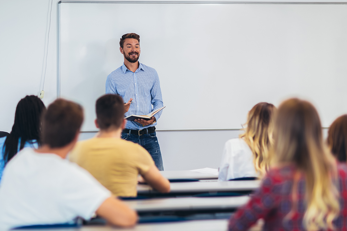 Ein Lehrer unterrichtet stehend erwachsene Personen