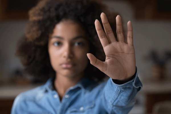 Frau hält Hand vor sich mit Schwirftzug "Stop"