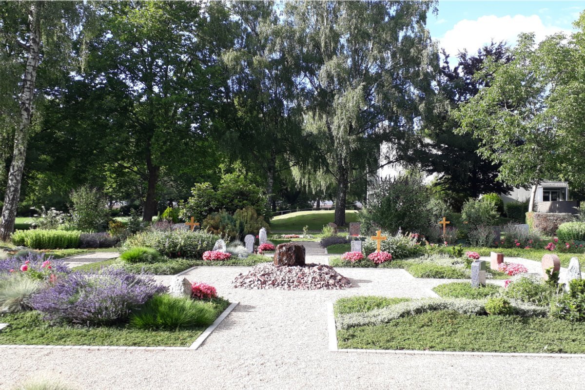 kreisförmige Wegeanlage mit Rasen und Blumen bepflanzten Urnengrabstellen