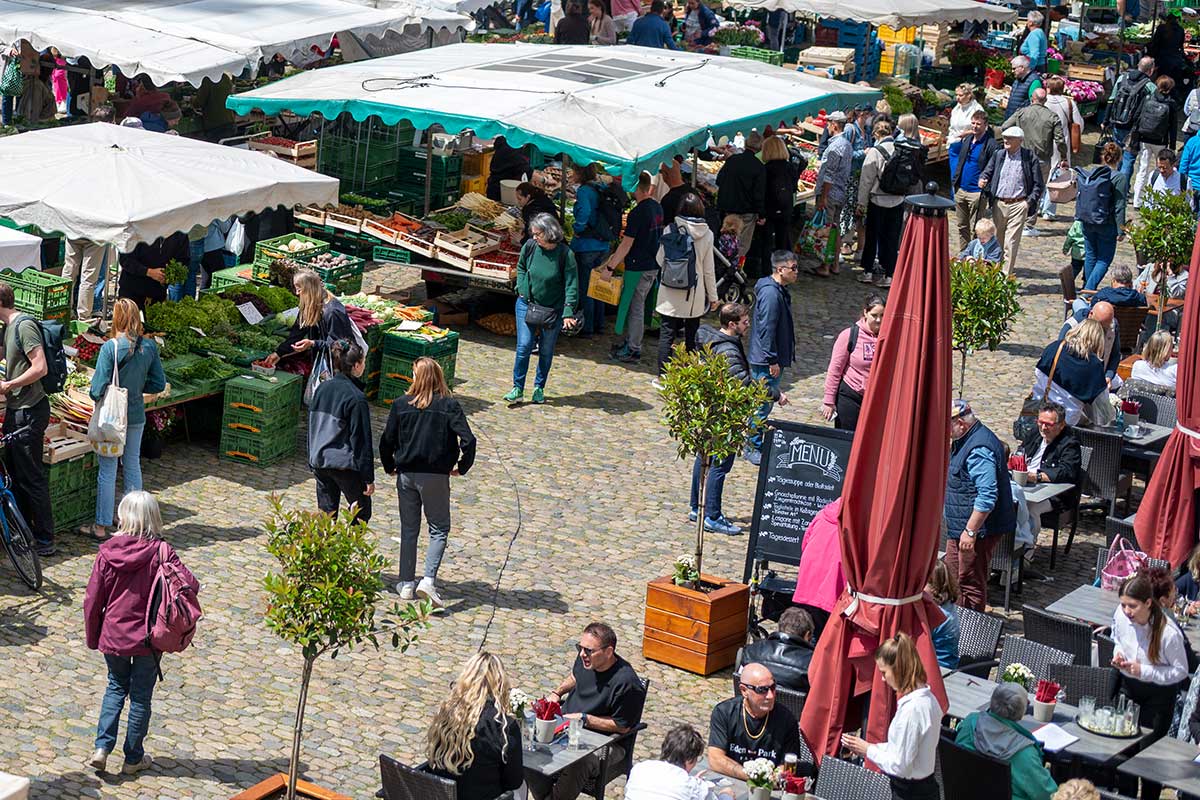 Marktstände, Kund*innen und Außenbestuhlung auf dem Münstermarkt
