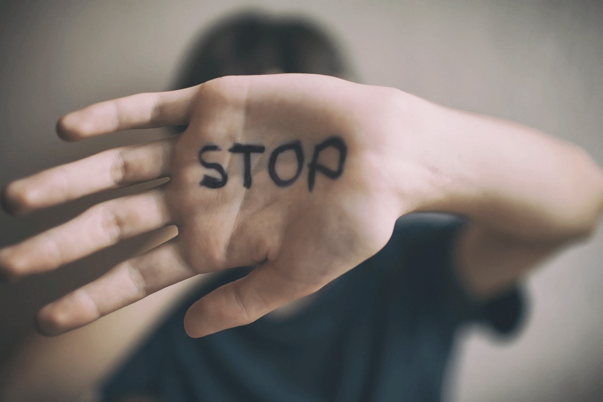 Frau hält Hand vor das Gesicht mit Schriftzug "Stop"