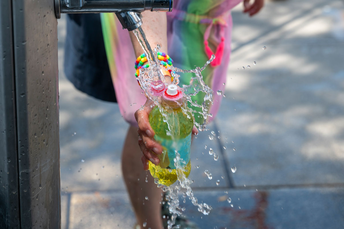 Person hält Flasche unter Wasserstele