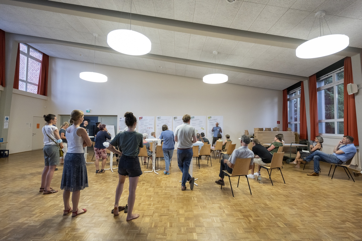 Stehende und sitzende Personen in einem Saal