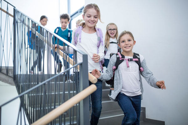 Eine Gruppe Schulkinder rennt fröhlich die Treppe herunter