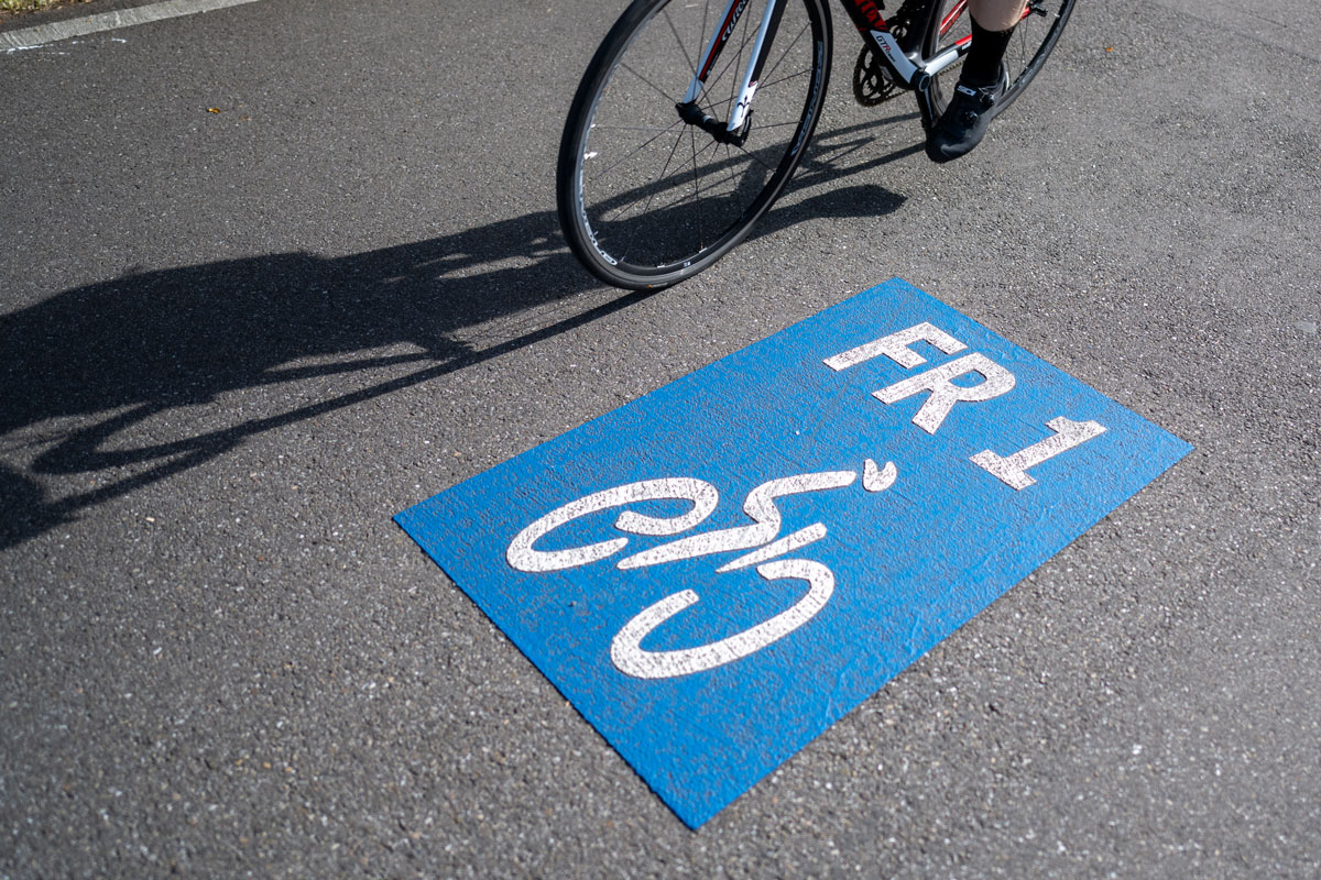 Logo FR1 auf Radweg, ein Fahrrad fährt im Hintergrund